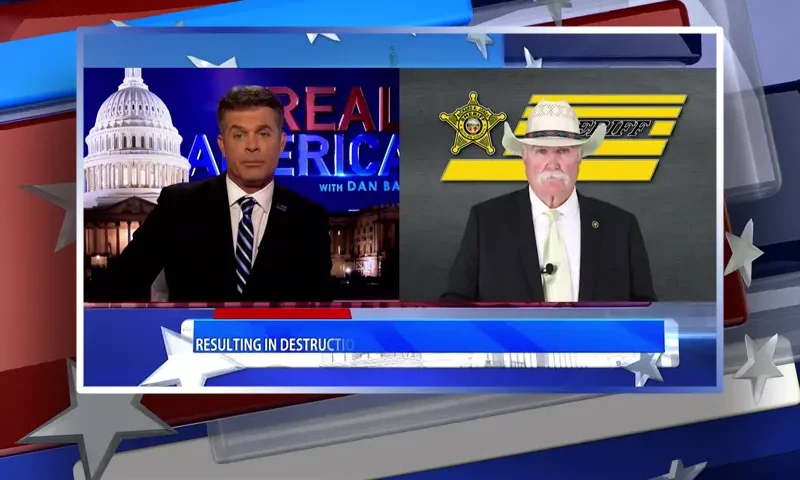 Video still from Real America on One America News Network showing a split screen of the host on the left side, and on the right side is the guest, Richard Jones.