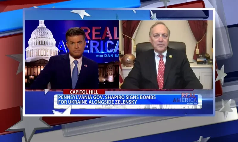 Video still from Real America on One America News Network showing a split screen of the host on the left side, and on the right side is the guest, Rep. Andy Biggs.