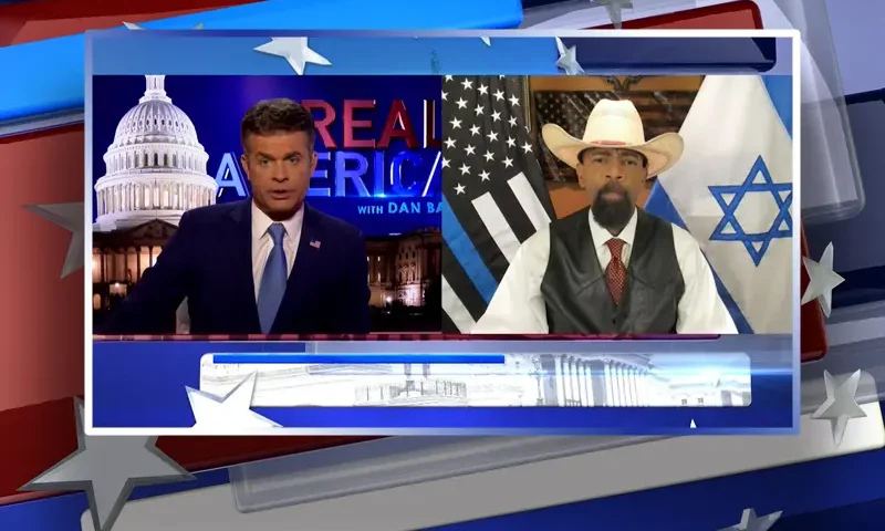 Video still from Real America on One America News Network showing a split screen of the host on the left side, and on the right side is the guest, Sheriff David Clarke.