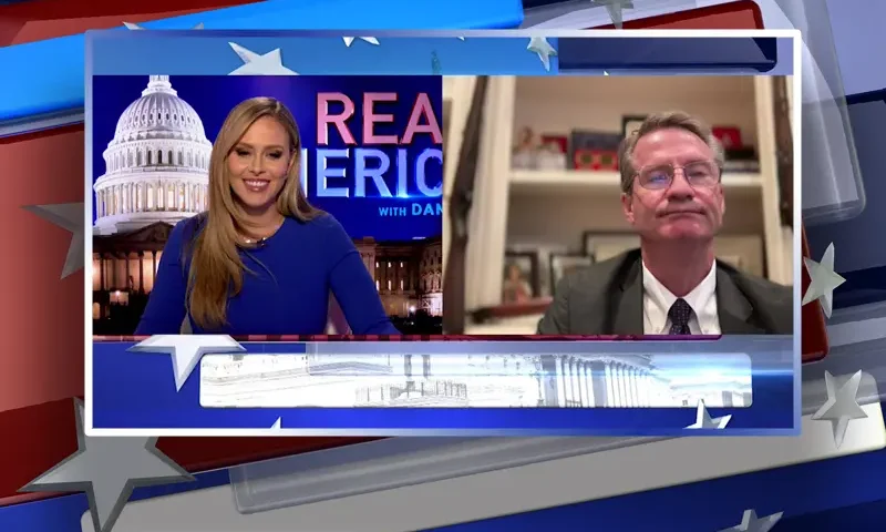 Video still from Real America on One America News Network showing a split screen of the host on the left side, and on the right side is the guest, Rep. Tim Burchett.