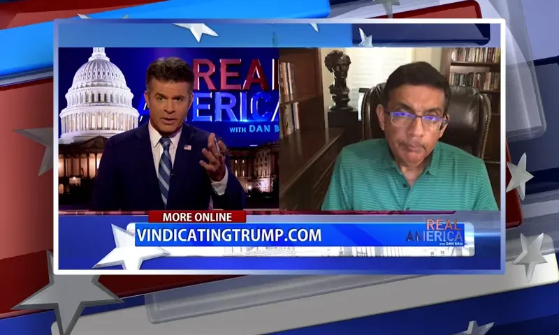Video still from Real America on One America News Network showing a split screen of the host on the left side, and on the right side is the guest, Dinesh D'Souza.