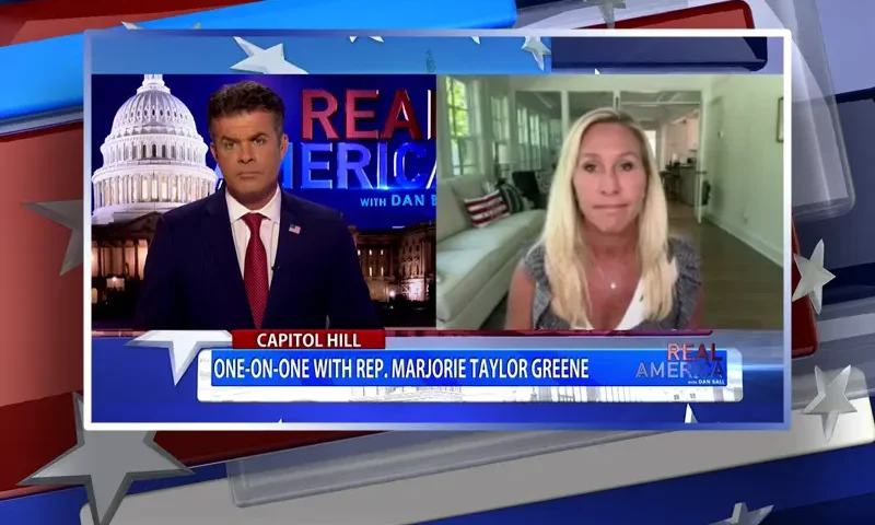 Video still from Real America on One America News Network showing a split screen of the host on the left side, and on the right side is the guest, Rep. Marjorie Taylor Greene.