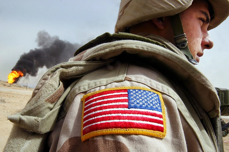 RUMAYLA, IRAQ - MARCH 27: U.S. Army Specialist Chad Morton, of George West, Texa,s stands next to a burning oil well at the Rumayla oil fields March 27, 2003 in Rumayla, Iraq. Several oil wells were set ablaze by retreating Iraqi troops in the Ramayla area, the second largest offshore oilfield in the country, near the Kuwaiti border. (Photo by Mario Tama/Getty Images)