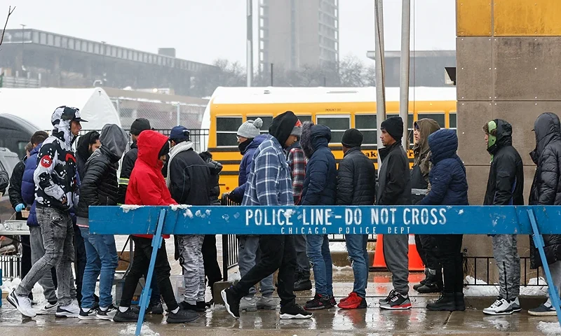 A group of migrants receives food outside the migrant landing zone during a winter storm on January 12, 2024 in Chicago, Illinois. Texas governor Greg Abbott, a staunch Republican, has sought to take the immigration debate nationwide by sending thousands of migrants to Democratic-led northern cities. (Photo by KAMIL KRZACZYNSKI / AFP) (Photo by KAMIL KRZACZYNSKI/AFP via Getty Images)