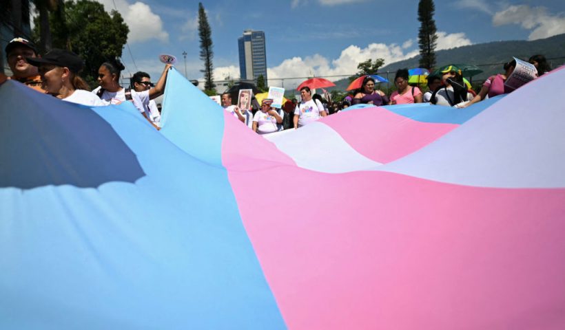 Members of LGBTQ+ groups hold a large Trans Pride flag during a rally marking International Day against homophobia, transphobia, and biphobia in San Salvador on May 18, 2024. (Photo by Marvin RECINOS / AFP) (Photo by MARVIN RECINOS/AFP via Getty Images)