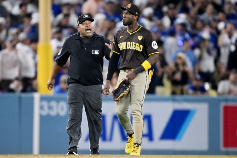 LOS ANGELES, CALIFORNIA - OCTOBER 06: Jurickson Profar #10 of the San Diego Padres walks across the field escorted by umpire Adrian Johnson after an incident with fans in the seventh inning against the Los Angeles Dodgers during Game Two of the Division Series at Dodger Stadium on October 06, 2024 in Los Angeles, California. (Photo by Orlando Ramirez/Getty Images)