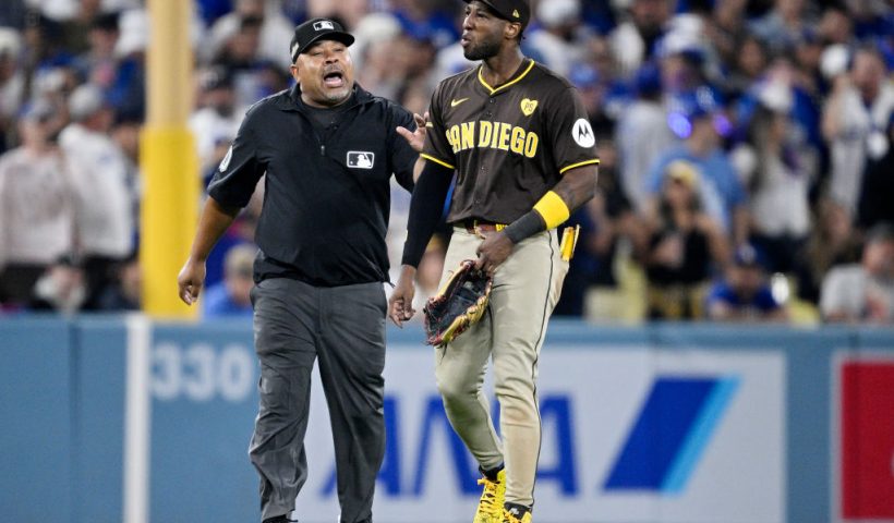 LOS ANGELES, CALIFORNIA - OCTOBER 06: Jurickson Profar #10 of the San Diego Padres walks across the field escorted by umpire Adrian Johnson after an incident with fans in the seventh inning against the Los Angeles Dodgers during Game Two of the Division Series at Dodger Stadium on October 06, 2024 in Los Angeles, California. (Photo by Orlando Ramirez/Getty Images)