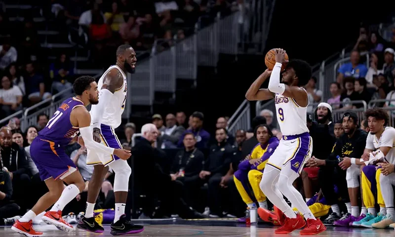 Bronny James #9 of the Los Angeles Lakers shoots against Tyus Jones #21 of the Phoenix Suns as teammate LeBron James #23 looks on during the second quarter at Acrisure Arena on October 06, 2024 in Palm Springs, California. (Photo by Katelyn Mulcahy/Getty Images)
