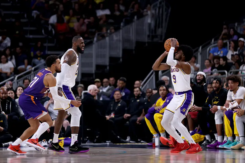 Bronny James #9 of the Los Angeles Lakers shoots against Tyus Jones #21 of the Phoenix Suns as teammate LeBron James #23 looks on during the second quarter at Acrisure Arena on October 06, 2024 in Palm Springs, California. (Photo by Katelyn Mulcahy/Getty Images)