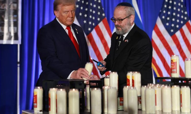 DORAL, FLORIDA - OCTOBER 07: Republican presidential nominee, former U.S. President Donald Trump, and Rabbi Yehuda Kaploun light a candle during an Oct. 7th remembrance event at the Trump National Doral Golf Club on October 07, 2024 in Doral, Florida. The event was held to commemorate October 7th, 2023, when Hamas terrorists mounted a series of attacks and raids on Israeli towns near Gaza, killing 1,145 people and taking 251 hostages. (Photo by Joe Raedle/Getty Images)