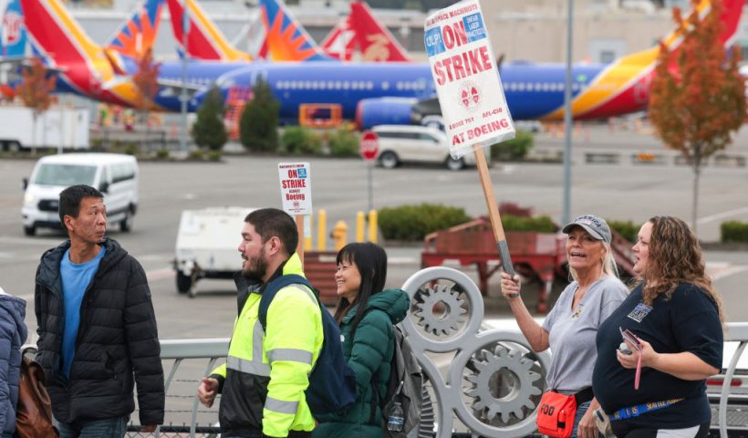 People carry Boeing-strike signs as they walk past parked Boeing 737 planes near Boeing Field following a strike rally for the International Association of Machinists and Aerospace Workers (IAM) at the Seattle Union Hall in Seattle, Washington, on October 15, 2024. (Photo by Jason Redmond / AFP) (Photo by JASON REDMOND/AFP via Getty Images)