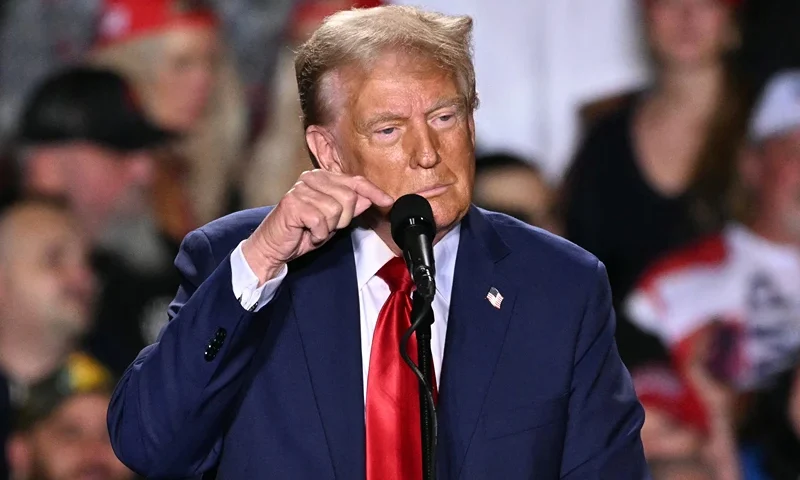 Former US President and Republican presidential candidate Donald Trump points to his microphone, which has gone out, leaving the audience unable to hear during a campaign rally at Huntington Place in Detroit, Michigan, October 18, 2024. (Photo by Jim WATSON / AFP) (Photo by JIM WATSON/AFP via Getty Images)