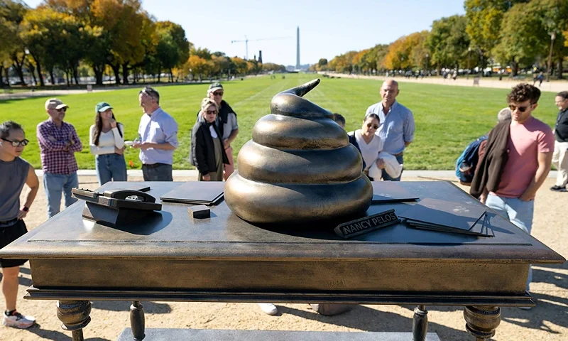TOPSHOT - People look at a bronze art installation depicting a pile of feces on former US Speaker of the House Nancy Pelosi's desk that is made to look like a monument by the group Civic Crafting to protest remarks by former US president and Republican presidential candidate Donald Trump's comments honoring the January 6, 2021 attack on the US Capitol, on the National Mall near the US Capitol in Washington, DC, on October 24, 2024. (Photo by SAUL LOEB / AFP) (Photo by SAUL LOEB/AFP via Getty Images)