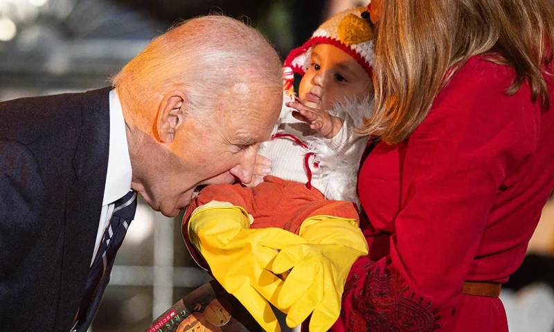 TOPSHOT - US President Joe Biden jokingly bites a baby dressed as a chicken as he hosts a Halloween trick-or-treat event at the South Portico of the White House in Washington, DC, on October 30, 2024. (Photo by Tierney CROSS / AFP) (Photo by TIERNEY CROSS/AFP via Getty Images)
