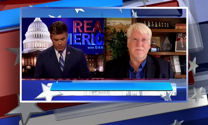 Video still from Real America on One America News Network showing a split screen of the host on the left side, and on the right side is the guest, Joe Hoft.