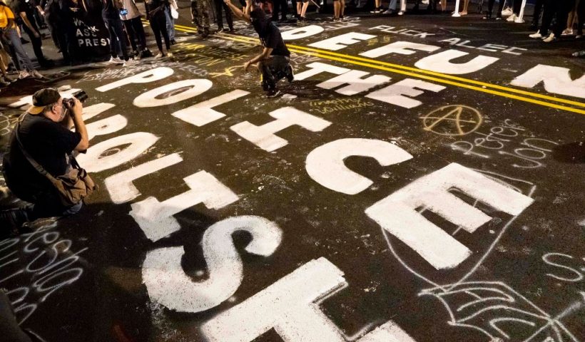 Demonstrators raise their fists around a mural dedicated to defund and abolish the police, during a rally to protest US President Donald Trump's acceptance of the Republican National Convention nomination at Black Lives Matter plaza across from the White House on August 27, 2020 in Washington, DC. - President Donald Trump accepts the Republican Party nomination for reelection tonight, August 27 against storm clouds of racial tension, riots and the coronavirus pandemic -- while warning of "chaos" should he lose to Democrat Joe Biden. (Photo by Jose Luis Magana / AFP) (Photo by JOSE LUIS MAGANA/AFP via Getty Images)