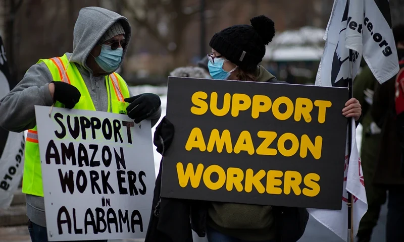 People hold placards during a protest in support of Amazon workers in Union Square, New York on February 20, 2021. - New York state's attorney general on February 17, 2021 sued Amazon, claiming the e-commerce giant failed to adequately protect its warehouse workers from risks during the Covid-19 pandemic. The move comes days after Amazon filed its own legal action seeking to block New York state Attorney General Letitia James from taking steps to enforce federal workplace safety regulations. (Photo by Kena Betancur / AFP) (Photo by KENA BETANCUR/AFP via Getty Images)