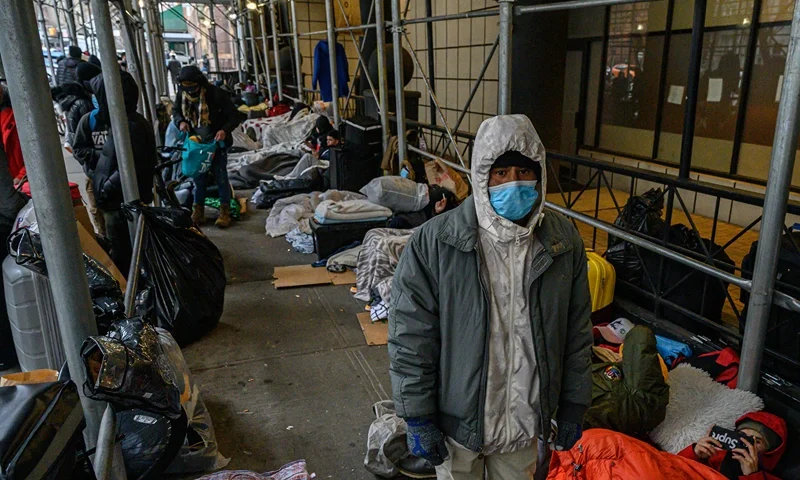 TOPSHOT - Migrants camp outside a hotel where they had previously been housed, as they resist efforts by the city to relocate them to a Brooklyn facility for asylum seekers, in the Hells Kitchen neighborhood of New York on January 31, 2023. - The Brooklyn facility is the city's fifth relief center amid a continued influx of asylum seekers, according to local media. (Photo by Ed JONES / AFP) (Photo by ED JONES/AFP via Getty Images)