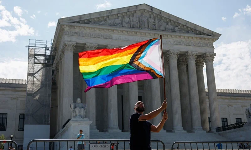 WASHINGTON, DC - JUNE 26: Same-sex marriage supporter Vin Testa, of Washington, DC, waves a LGBTQIA pride flag in front of the U.S. Supreme Court Building as he makes pictures with his friend Donte Gonzalez to celebrate the anniversary of the United States v. Windsor and the Obergefell v. Hodges decisions on June 26, 2023 in Washington, DC. Today marks the 8th anniversary of the Supreme Court's ruling in the Obergefell v. Hodges case that guaranteed the right to marriage for same-sex couples. (Photo by Anna Moneymaker/Getty Images)
