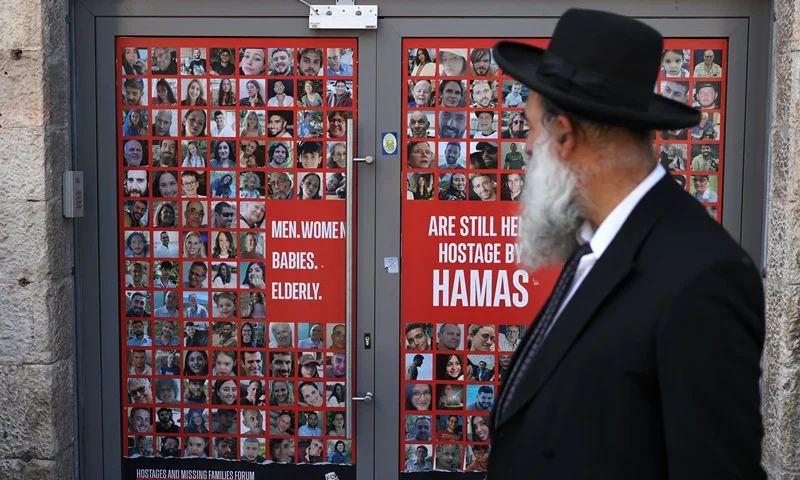 TOPSHOT - An Israeli walks past a store entrance displaying a banner with the portraits of Israelis held hostage by Palestinian militants in Gaza since the October 7 2023 attacks, in Jerusalem's King George street on October 13, 2024. (Photo by HAZEM BADER / AFP) (Photo by HAZEM BADER/AFP via Getty Images)