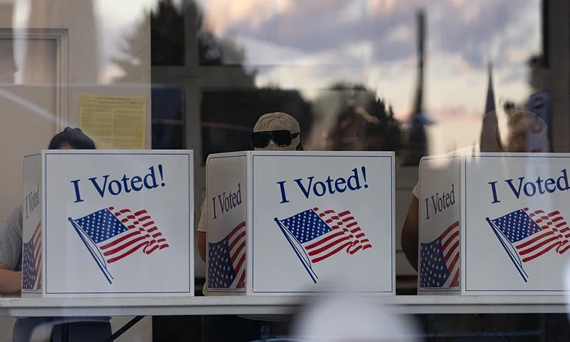 People complete their ballots as the sunset is reflected in the glass of a precinct in the Bloomfield neighborhood of Pittsburgh, Pennsylvania, on November 5, 2024. (Photo by Rebecca DROKE / AFP) (Photo by REBECCA DROKE/AFP via Getty Images)