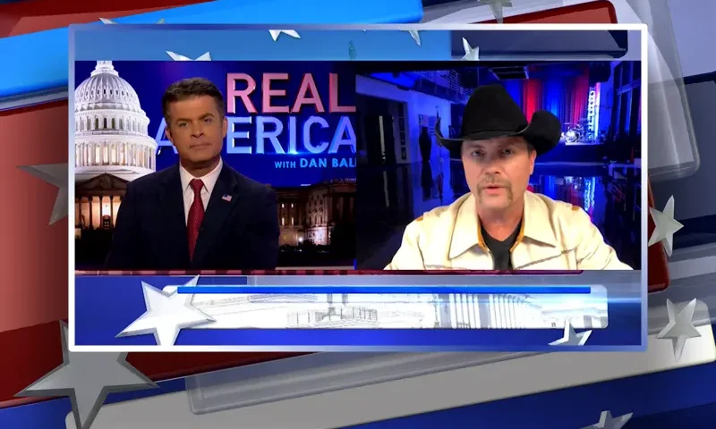 Video still from Real America on One America News Network showing a split screen of the host on the left side, and on the right side is the guest, John Rich.