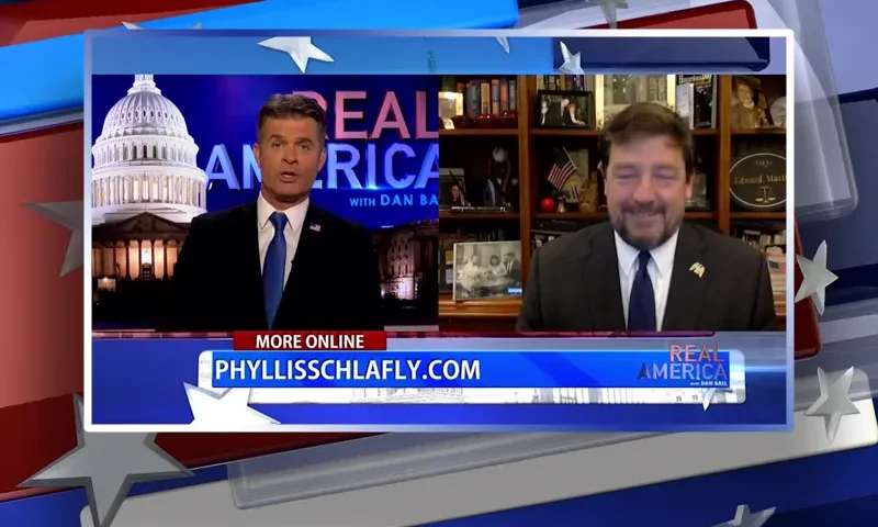 Video still from Real America on One America News Network showing a split screen of the host on the left side, and on the right side is the guest, Ed Martin.
