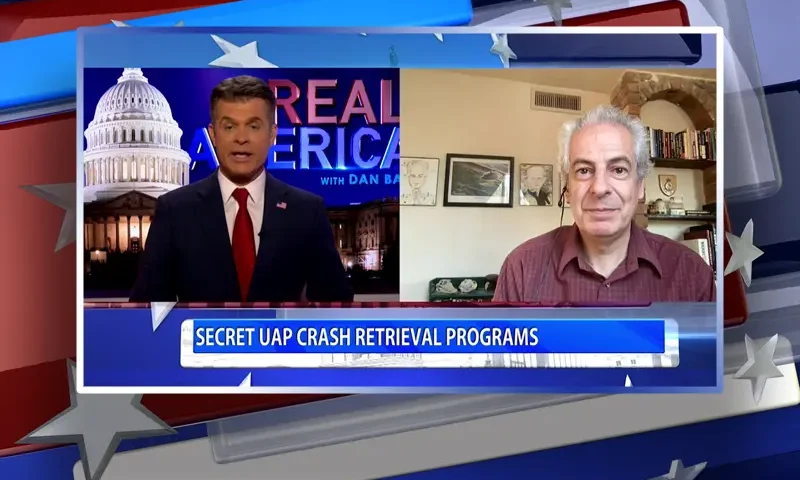 Video still from Real America on One America News Network showing a split screen of the host on the left side, and on the right side is the guest, Nick Pope.