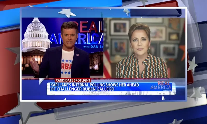 Video still from Real America on One America News Network showing a split screen of the host on the left side, and on the right side is the guest, Kari Lake.