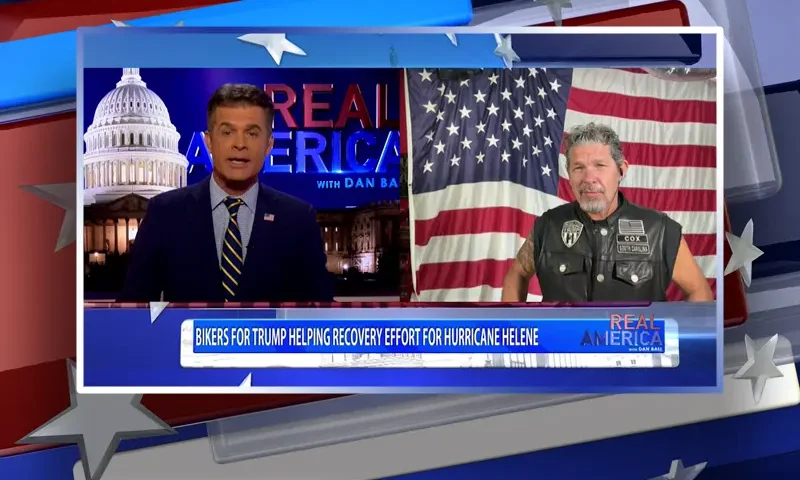 Video still from Real America on One America News Network showing a split screen of the host on the left side, and on the right side is the guest, Chris Cox.