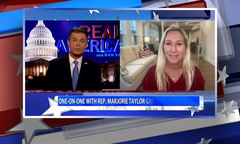 Video still from Real America on One America News Network showing a split screen of the host on the left side, and on the right side is the guest, Rep. Marjorie Taylor Greene.