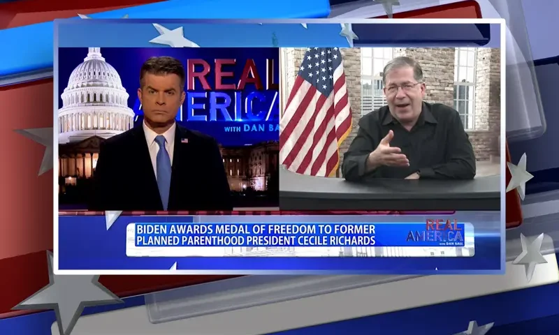 Video still from Real America on One America News Network showing a split screen of the host on the left side, and on the right side is the guest, Frank Pavone.