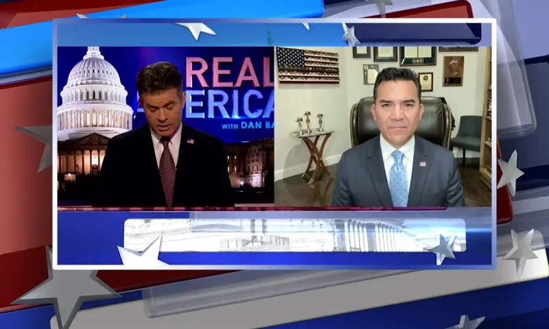 Video still from Real America on One America News Network showing a split screen of the host on the left side, and on the right side is the guest, Victor Avila.