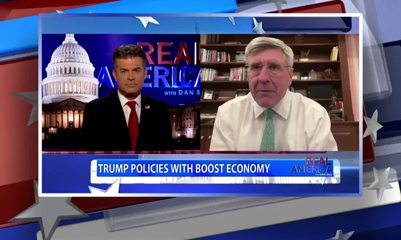 Video still from Real America on One America News Network showing a split screen of the host on the left side, and on the right side is the guest, Stephen Moore.