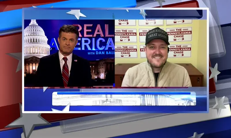 Video still from Real America on One America News Network showing a split screen of the host on the left side, and on the right side is the guest, Cliff Maloney.