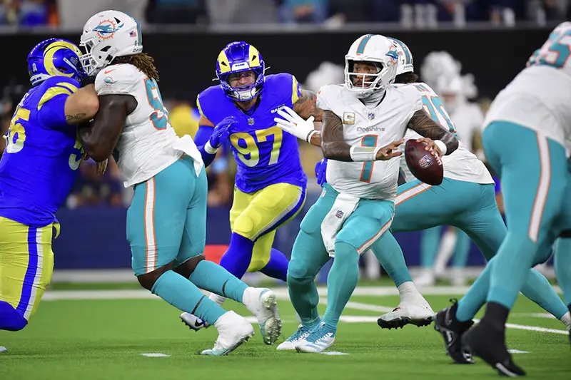 Miami Dolphins quarterback Tua Tagovailoa (1) moves out to pass as Los Angeles Rams linebacker Michael Hoecht (97) moves in during the first half at SoFi Stadium. Mandatory Credit: Gary A. Vasquez-Imagn Images