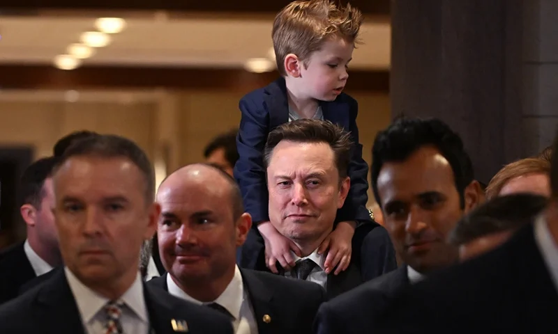 TOPSHOT - Tesla CEO Elon Musk (C), co-chair of the newly created Department of Government Efficiency (DOGE), carries his son "X" on his shoulders before a meeting with members of Congress at the US Capitol in Washington, DC, on December 5, 2024. President-elect Trump rewarded the Tesla, X and SpaceX chief for his support in the White House race by naming him head of the newly created Department of Government Efficiency, along with another wealthy ally, Vivek Ramaswamy. (Photo by ROBERTO SCHMIDT / AFP) (Photo by ROBERTO SCHMIDT/AFP via Getty Images)