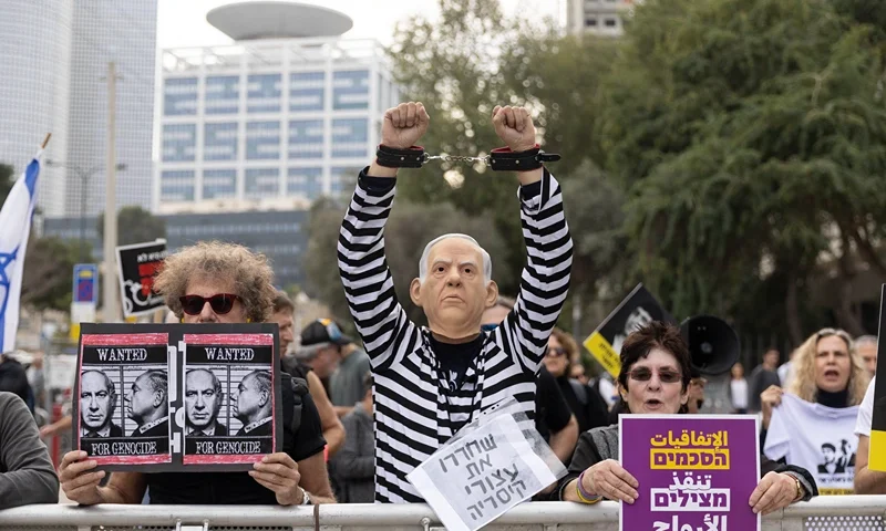 TEL AVIV, ISRAEL - DECEMBER 10: A protester dressed as Netanyahu in a prisoner uniform during a demonstration against Israeli Prime Minister Benjamin Netanyahu outside Tel Aviv's court as Netanyahu testifies in a corruption trial on December 10, 2024 in Tel Aviv, Israel. Netanyahu was indicted in 2019 on charges of bribery, fraud and breach of trust. The trial began in 2020 and involves three criminal cases. He denies the charges and has pleaded not guilty. (Photo by Amir Levy/Getty Images)