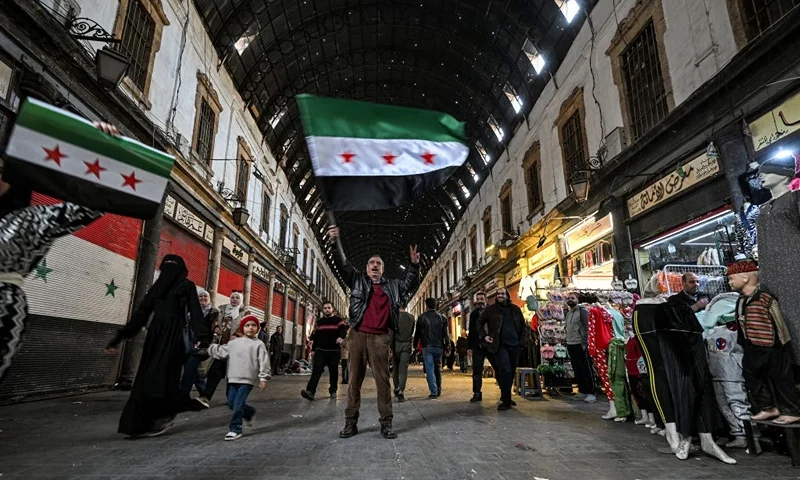 A man reacts as he holds up a Syrian opposition flag along an alley of the Hamidiyah covered market in the old part of Damascus on December 10, 2024. Islamist-led rebels took Damascus in a lightning offensive on December 8, ousting president Bashar al-Assad and ending five decades of Baath rule in Syria. (Photo by LOUAI BESHARA / AFP) (Photo by LOUAI BESHARA/AFP via Getty Images)