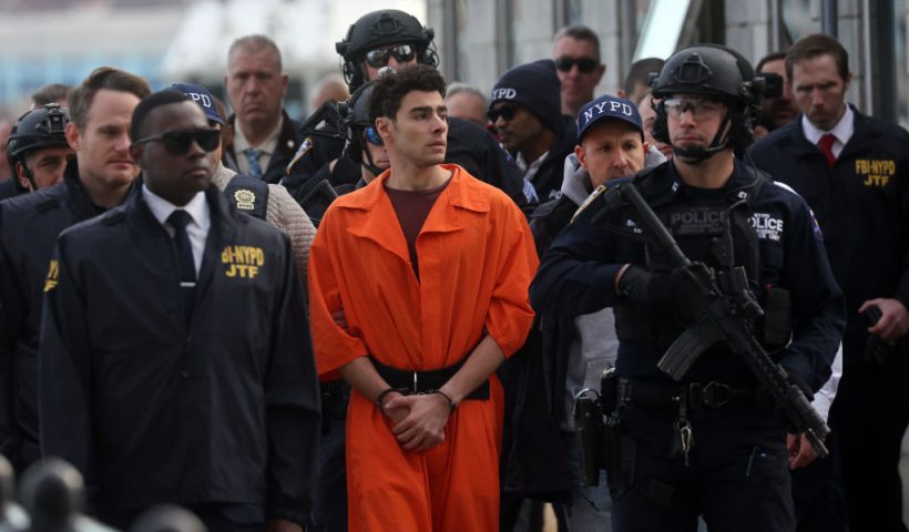 NEW YORK, NEW YORK - DECEMBER 19: Luigi Mangione, suspect in the killing of UnitedHealthcare CEO Brian Thompson in New York City, arrives at a heliport with members of the NYPD on December 19, 2024 in New York City. The 26-year-old was arrested in Pennsylvania on December 9 after being spotted at a McDonald's in Altoona amid a national manhunt. Mangione also appeared in a Pennsylvania court on forgery and firearms charges today, where he waived extradition to New York after being indicted on 11 charges including first-degree murder in furtherance of terrorism. (Photo by Spencer Platt/Getty Images)