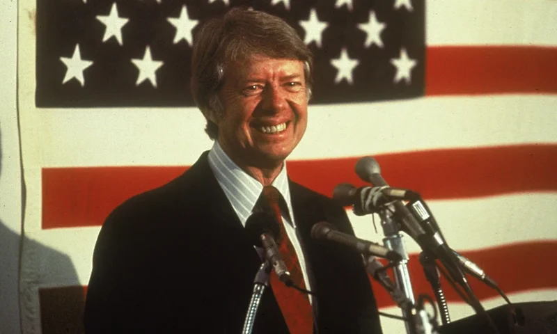 U.S. president Jimmy Carter smiling at a podium in front of an American flag, 1970s. (Photo by Hulton Archive/Getty Images)