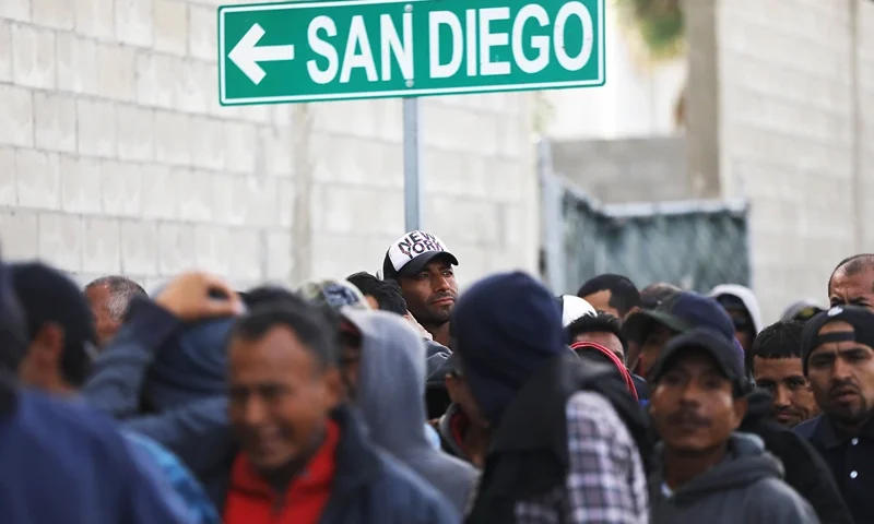 TIJUANA, MEXICO - MARCH 09: Migrants line up for free breakfast at the Desayunador Salesiano Padre Chava shelter and soup kitchen in front of sign for San Diego on March 9, 2018 in Tijuana, Mexico. The soup kitchen receives between 1,000-1,200 migrants daily, most of whom have been deported from the United States. Deportees sometimes end up homeless on the streets of Tijuana. (Photo by Mario Tama/Getty Images)