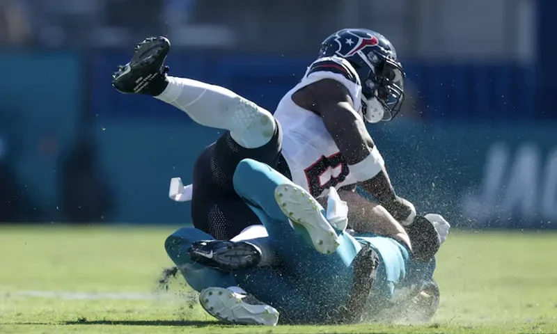 Jacksonville Jaguars quarterback Trevor Lawrence (16) is hit by Houston Texans linebacker Azeez Al-Shaair (0) as he slides down in the second quarter in the second quarter at EverBank Stadium. Mandatory Credit: Nathan Ray Seebeck-Imagn Images/File Photo