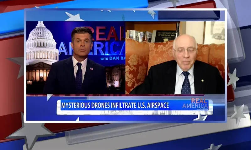 Video still from Real America on One America News Network showing a split screen of the host on the left side, and on the right side is the guest, Lt. Col. Robert Maginnis.