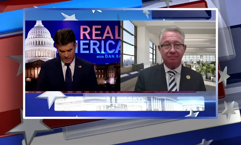 Video still from Real America on One America News Network showing a split screen of the host on the left side, and on the right side is the guest, Bill Wells.