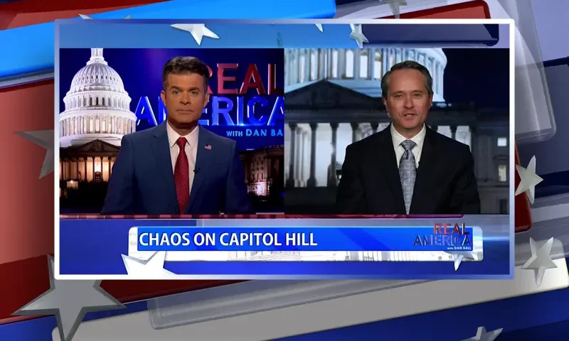 Video still from Real America on One America News Network showing a split screen of the host on the left side, and on the right side is the guest, John Hart.