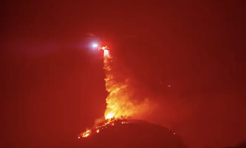 A helicopter drops water as the Hughes Fire burns near Castaic Lake, north of Santa Clarita, California, U.S. January 22, 2025. REUTERS/Ringo Chiu/File Photo