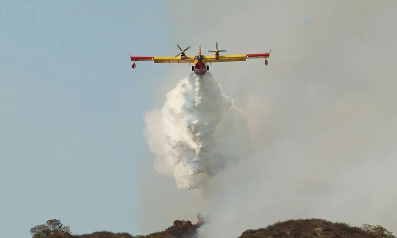 GLENDALE, CA - SEPTEMBER 9: A CL-215 "Super Scooper" air tanker drops a white cloud of water instead of the usual red fire retardant used by other air bombers at a wildfire September 9, 2002 in Glendale, California. The "Super Scooper," which scoops up water as it flies across a lake surface, is popular among politicians but some fire bosses are not yet sold on the new aircraft as a cost-effective means of suppressing fire. Homes were threatened today but none were lost in the 800-plus acre wildfire burning in the Los Angeles suburbs of Glendale and Burbank. Containment of the fire is set at 20 percent. (Photo by David McNew/Getty Images)