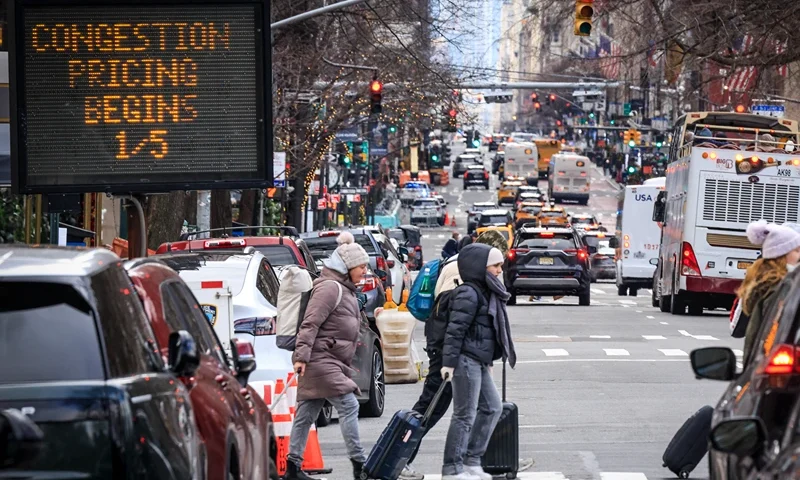 Pedestrians walk past a congestion pricing warning sign on 5th Avenue as congestion pricing begins taking effect in New York City on January 05, 2024. On Sunday New York is reviving a controversial scheme to charge drivers entering parts of the city, a first in the United States, putting local authorities on a collision course with President-elect Donald Trump. (Photo by KENA BETANCUR / AFP) (Photo by KENA BETANCUR/AFP via Getty Images)