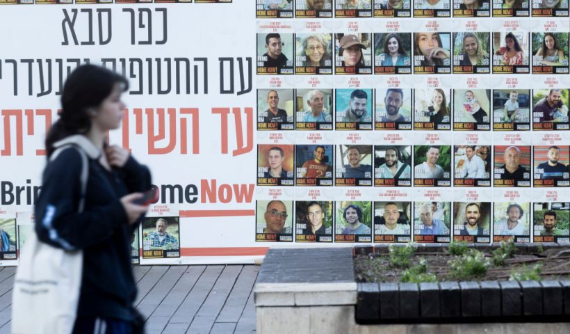KFAR SABA, ISRAEL - JANUARY 6: A woman passes by a wall covered with photos of hostages that were kidnaped to the Gaza Strip during Hamas deadly attack on January 6, 2025 in Kfar Saba, Israel. Israel and Hamas resumed indirect ceasefire talks through mediators in Qatar, as Israel continued airstrikes in Gaza over the weekend. (Photo by Amir Levy/Getty Images)